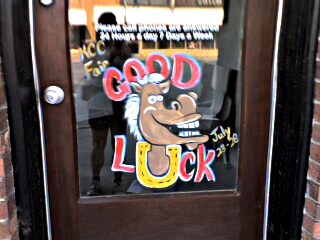 [Good luck (with a horshoe for the u) written around a smiling horse. This is painted on a door on a business on the main street.]